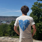 weißes T-Shirt mit blauem herz Backprint wird von einem Mann getragen, der über eine Stadt blickt. 